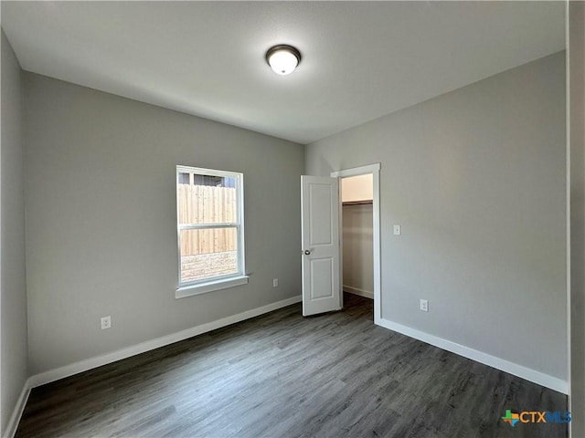 unfurnished bedroom featuring dark wood-type flooring and a walk in closet