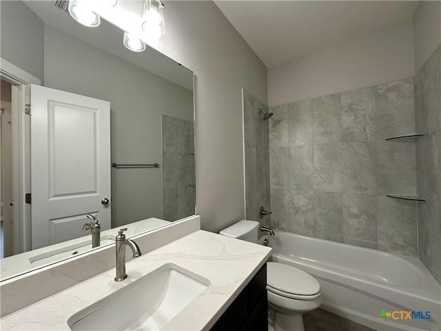 full bathroom featuring tiled shower / bath combo, vanity, and toilet