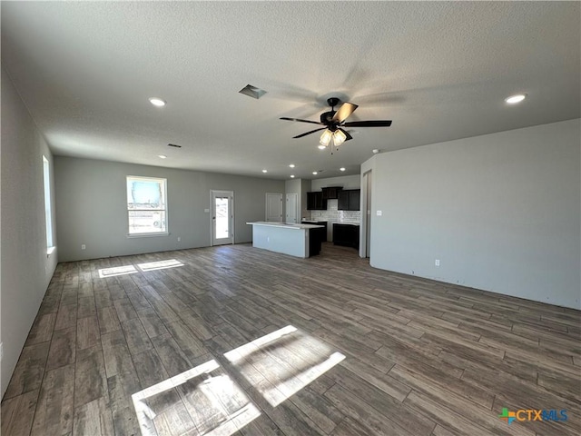 unfurnished living room with dark hardwood / wood-style flooring, a textured ceiling, and ceiling fan