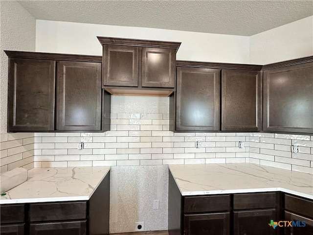 kitchen featuring dark brown cabinetry, decorative backsplash, and a textured ceiling