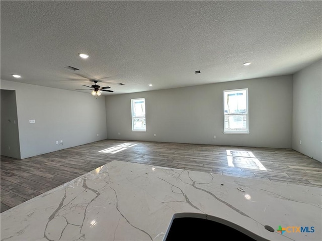 spare room featuring a textured ceiling, ceiling fan, and light hardwood / wood-style flooring