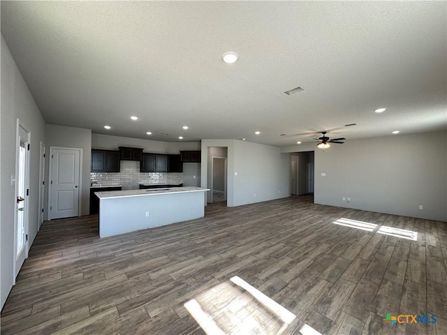 kitchen with a kitchen island, dark hardwood / wood-style flooring, decorative backsplash, ceiling fan, and a textured ceiling