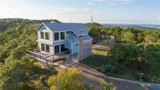 461 Naked Indian Trl, New Braunfels, TX 78132 - back of house with a standing seam roof, a deck, metal roof, a chimney, and a forest view