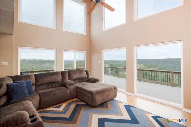 living room featuring hardwood / wood-style floors, ceiling fan, and a high ceiling