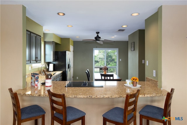 kitchen with sink, kitchen peninsula, a kitchen breakfast bar, stainless steel refrigerator with ice dispenser, and ceiling fan