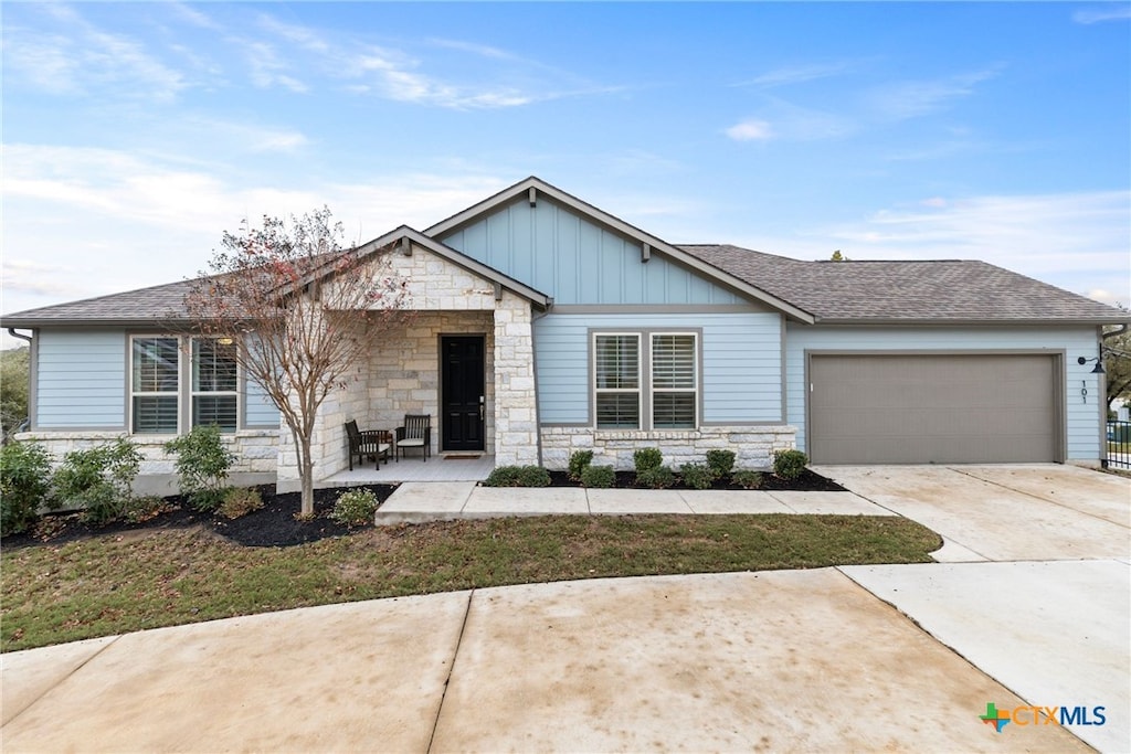 view of front of property with board and batten siding, concrete driveway, stone siding, and an attached garage