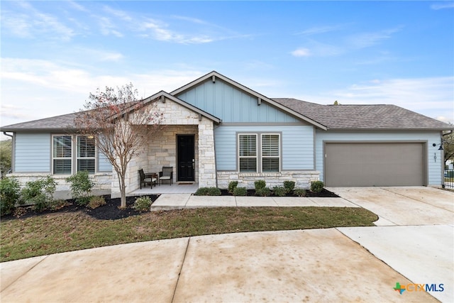 view of front of property with board and batten siding, concrete driveway, stone siding, and an attached garage