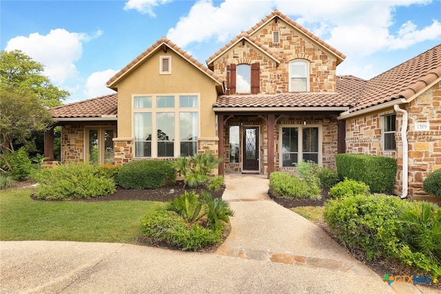 view of front of house featuring stone siding, a tiled roof, and stucco siding