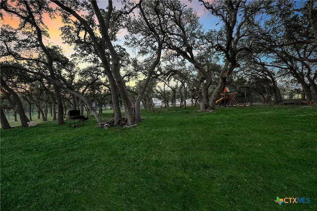 yard at dusk featuring a playground