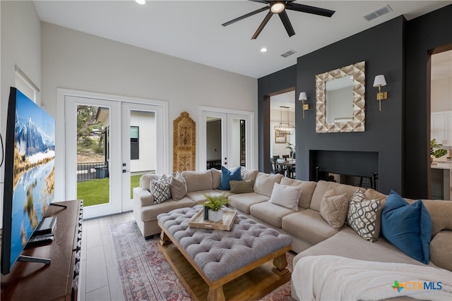 living room with french doors, a fireplace, wood-type flooring, and ceiling fan