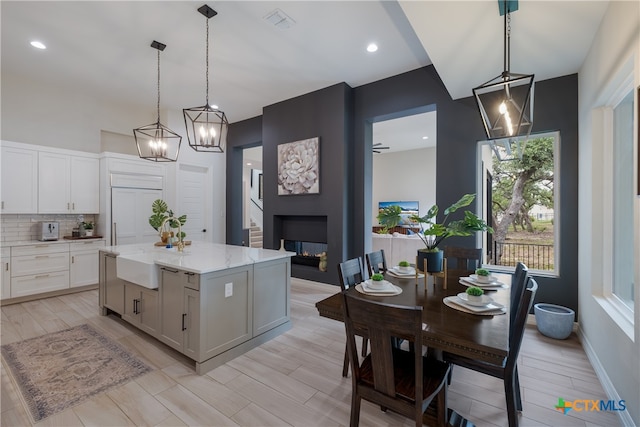 kitchen with a kitchen island, white cabinetry, a large fireplace, and decorative light fixtures