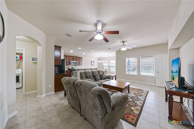 living room with arched walkways, visible vents, baseboards, and light tile patterned floors