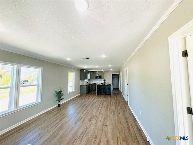 unfurnished living room featuring a textured ceiling, crown molding, and light hardwood / wood-style flooring