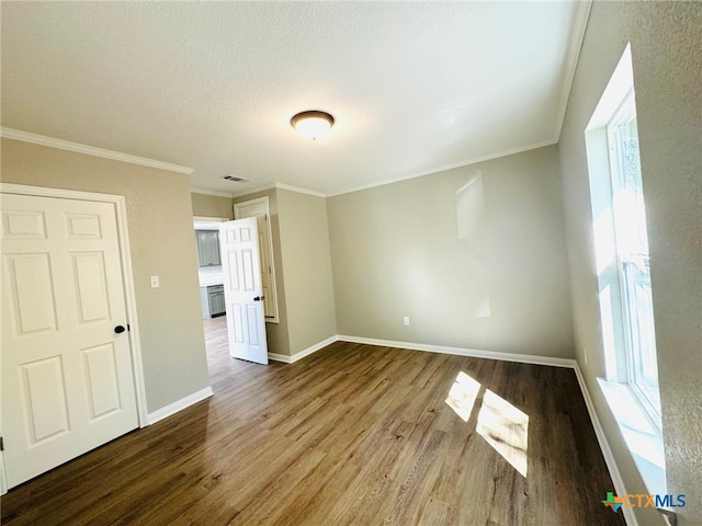 interior space featuring a textured ceiling, hardwood / wood-style flooring, and crown molding