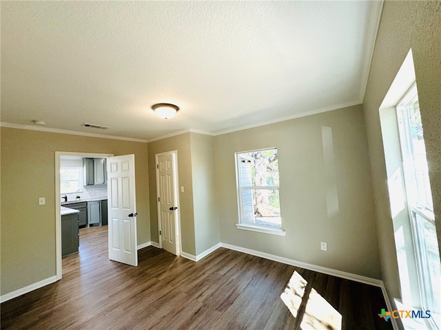 spare room featuring dark hardwood / wood-style flooring, a wealth of natural light, and ornamental molding