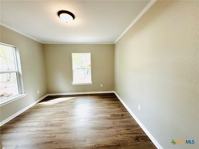 spare room featuring a wealth of natural light, wood-type flooring, and crown molding