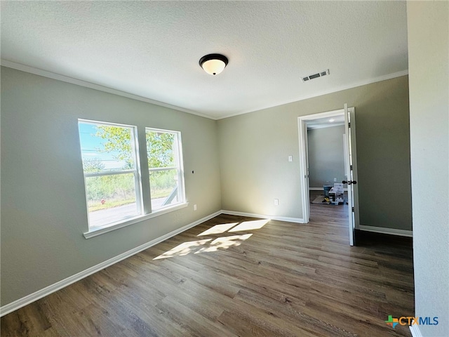 spare room with crown molding, a textured ceiling, and dark hardwood / wood-style flooring