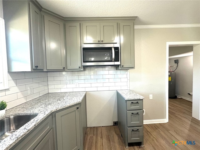 kitchen with electric water heater, tasteful backsplash, dark hardwood / wood-style floors, and crown molding