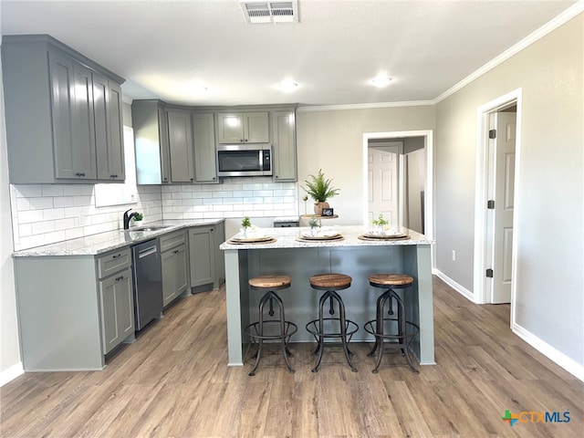 kitchen featuring a kitchen island, light stone countertops, wood-type flooring, and stainless steel appliances