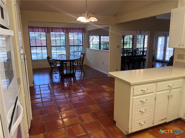 tiled dining room with an inviting chandelier and vaulted ceiling