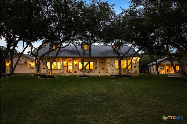 29720 Twin Creeks Dr, Bulverde, TX 78163 - back of house at dusk with a yard, stone siding, and a metal roof
