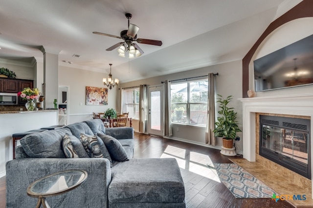 living room featuring ornamental molding, dark hardwood / wood-style flooring, a tile fireplace, and ceiling fan with notable chandelier