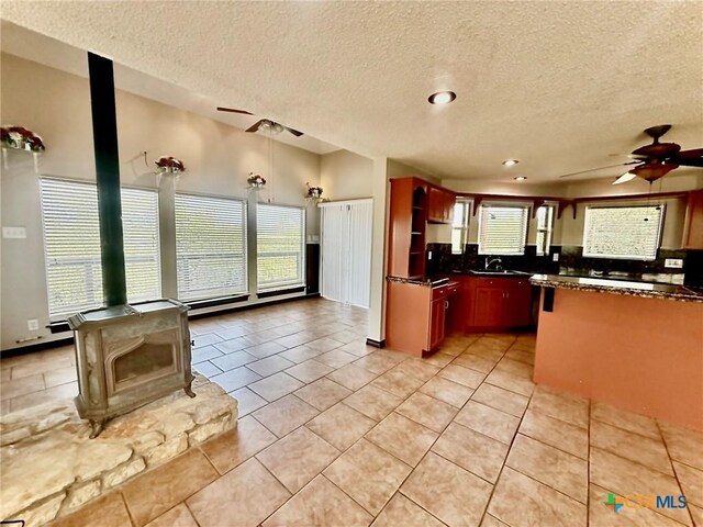 1795 Falconwood Dr, San Marcos, TX 78666 - kitchen featuring ceiling fan, a textured ceiling, dark countertops, a wood stove, and recessed lighting