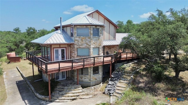1795 Falconwood Dr, San Marcos, TX 78666 - rear view of property with stone siding, french doors, a standing seam roof, a deck, and a garage