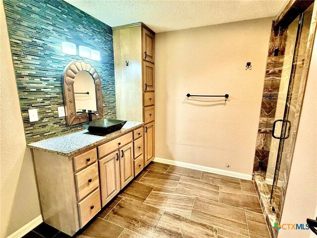 1795 Falconwood Dr, San Marcos, TX 78666 - bathroom featuring vanity, a stall shower, a textured ceiling, and decorative backsplash