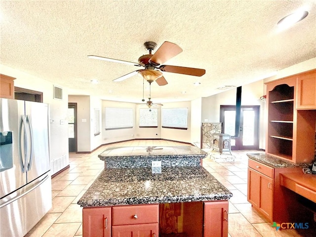 1795 Falconwood Dr, San Marcos, TX 78666 - kitchen featuring freestanding refrigerator, a textured ceiling, ceiling fan, light tile patterned flooring, and a center island