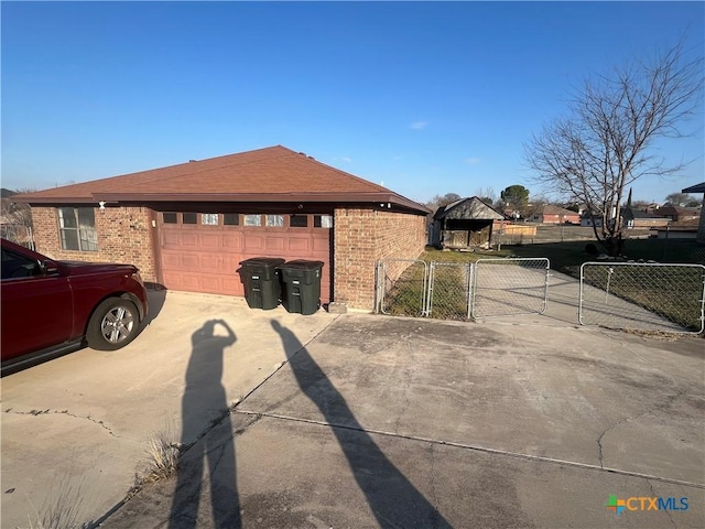 view of home's exterior featuring a gate, fence, driveway, an attached garage, and brick siding