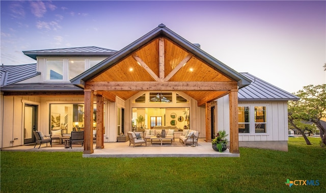 back house at dusk with a lawn, a patio area, and an outdoor living space