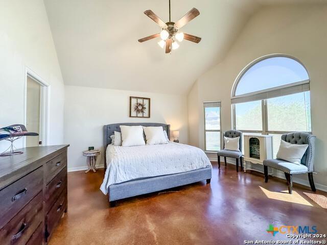 bedroom featuring baseboards, high vaulted ceiling, ceiling fan, and finished concrete flooring