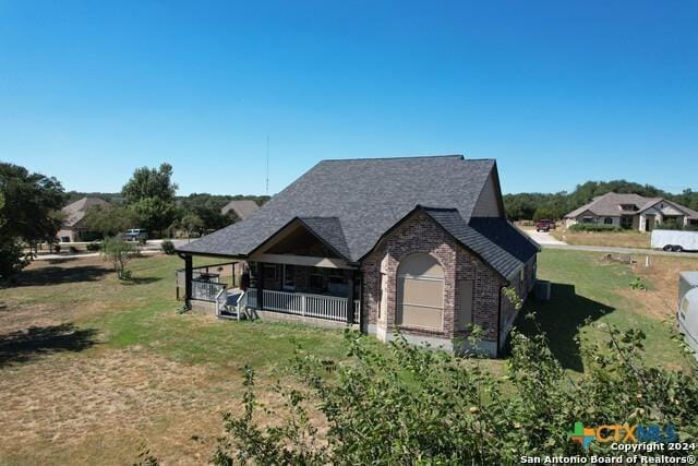 exterior space with brick siding, a front lawn, and roof with shingles