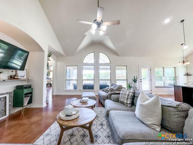 living area with baseboards, high vaulted ceiling, a ceiling fan, and finished concrete flooring