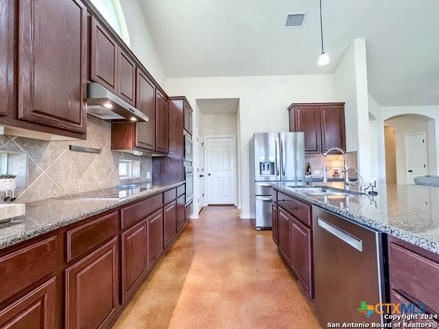 kitchen featuring visible vents, under cabinet range hood, appliances with stainless steel finishes, arched walkways, and a sink