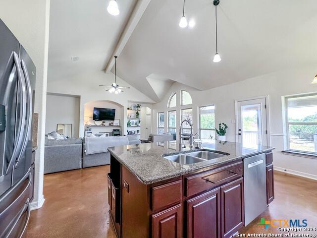 kitchen featuring a kitchen island with sink, a sink, hanging light fixtures, stainless steel appliances, and beamed ceiling