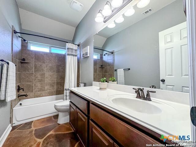 bathroom featuring visible vents, toilet, vaulted ceiling, vanity, and shower / bathtub combination with curtain