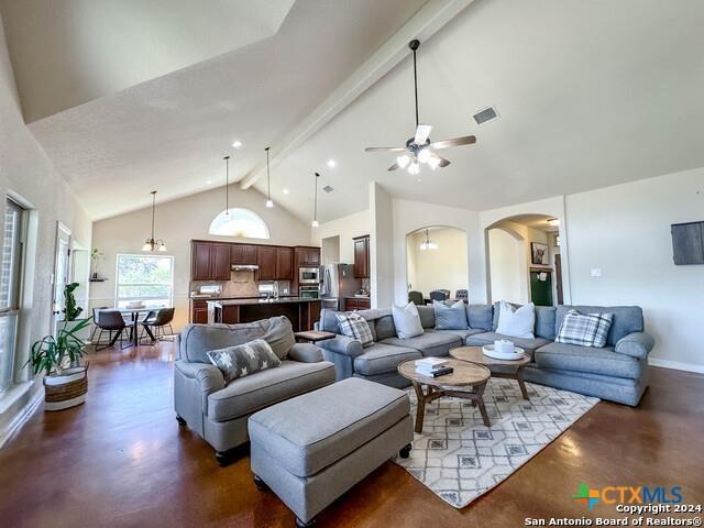 living area with visible vents, ceiling fan, concrete flooring, beam ceiling, and high vaulted ceiling