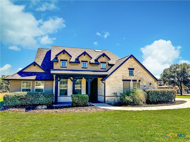 view of front facade featuring a front lawn, stone siding, and stucco siding