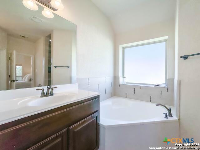 full bathroom featuring lofted ceiling, ensuite bath, a bath, and vanity