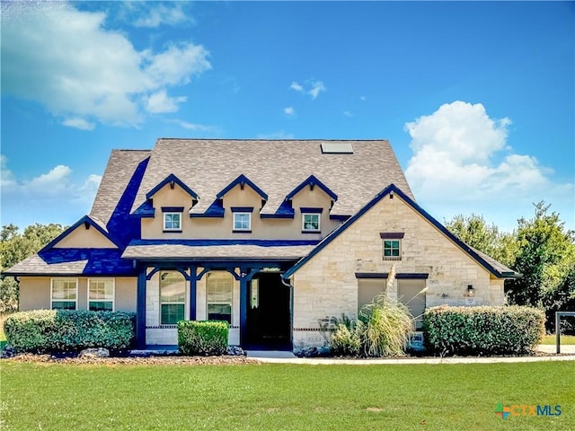 view of front facade with a shingled roof, a front lawn, stone siding, and stucco siding