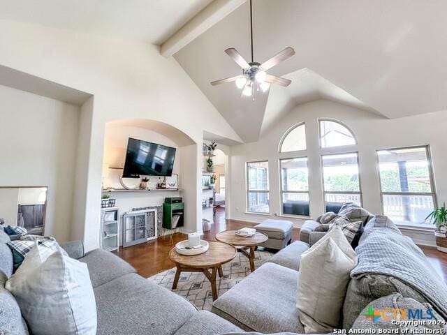 living area with wood finished floors, beamed ceiling, a ceiling fan, and high vaulted ceiling