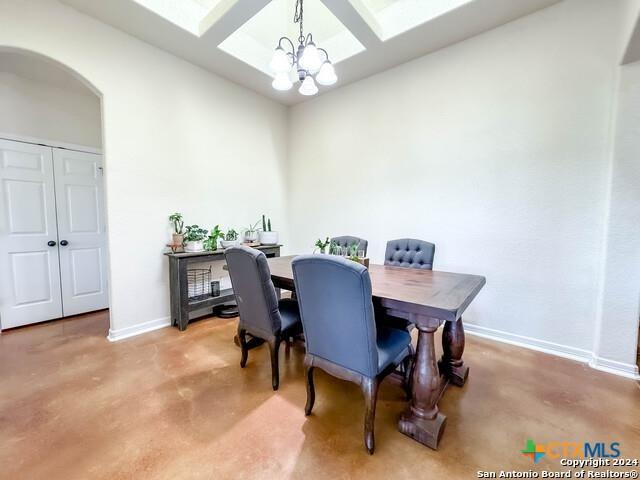 dining area featuring baseboards, a skylight, arched walkways, a notable chandelier, and coffered ceiling