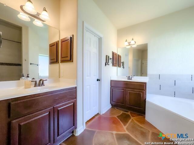 full bathroom with a sink, two vanities, and a bath