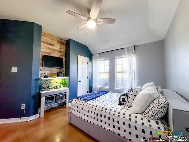 bedroom with a closet, wood walls, baseboards, ceiling fan, and vaulted ceiling