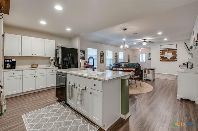 kitchen with white cabinets, an island with sink, sink, and black appliances