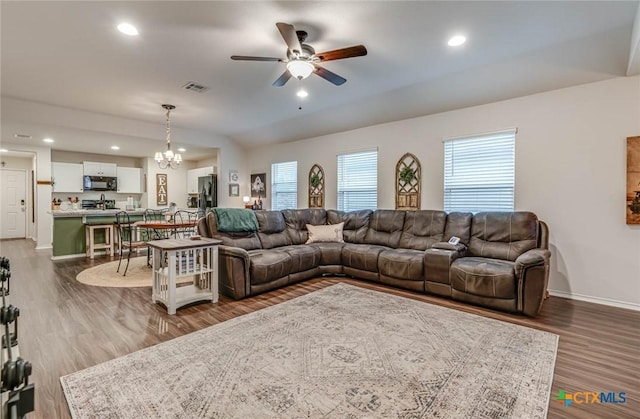 living room with hardwood / wood-style flooring and ceiling fan with notable chandelier