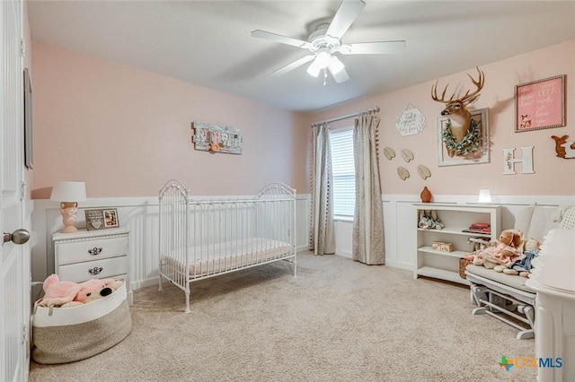 carpeted bedroom with a nursery area and ceiling fan