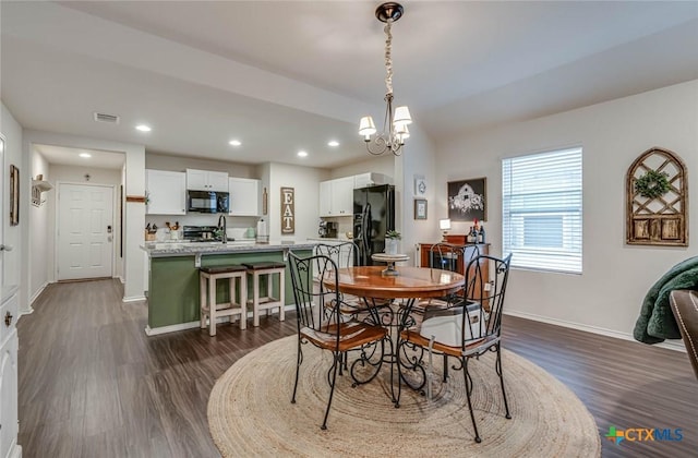 dining area featuring dark hardwood / wood-style flooring, sink, and a chandelier